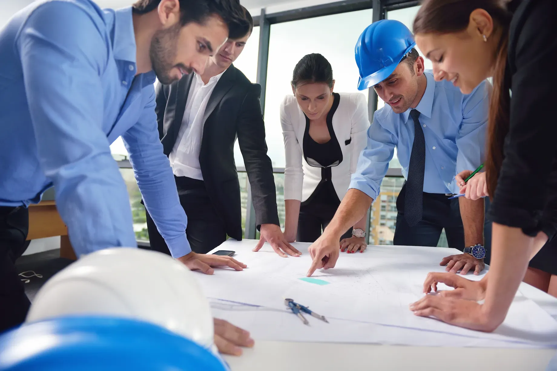 Engineer drafting site plans with a scale ruler and rolled drawings